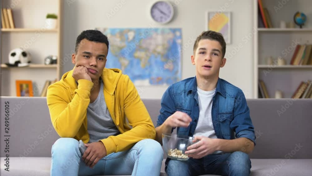 Bored multiracial boys watching TV eating snacks, slow old technology connection Bored multiracial boys watching TV eating snacks, slow old technology connection