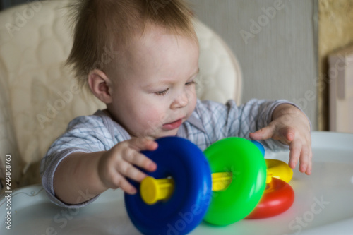happy toddler baby boy sorting colorful rings on pyramid
