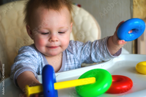 happy toddler baby boy sorting colorful rings on pyramid