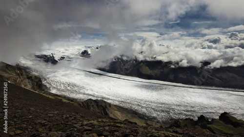 Skaftafellsjokull glacier "flowing" diagonally across photo with clouds above the glacier and mountains in background in Skaftafell National Park, Southern Iceland.