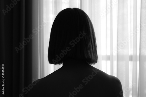 black and white silhouette of young girl with bob haircut in window