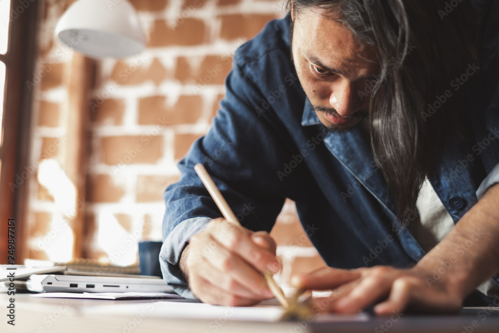 Young Asian man draft a drawing plan for artwork, architect, engineering drawing, creative designer concept Young Asian man draft a drawing plan for artwork, architect, engineering drawing, creative designer concept