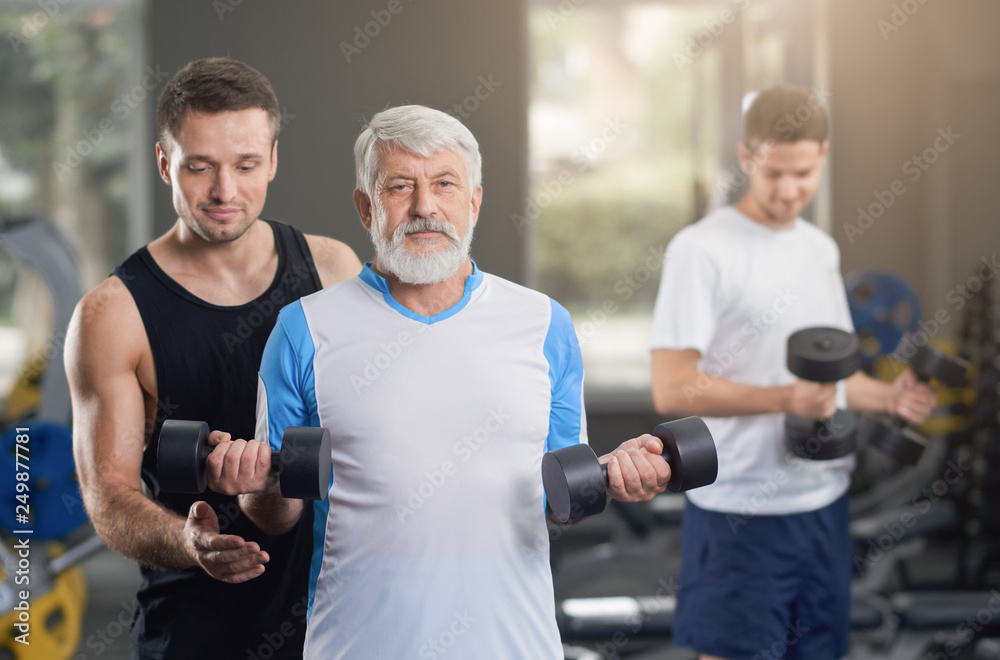 Fit trainer helping people in gym to work out. Fit trainer helping people in gym to work out.