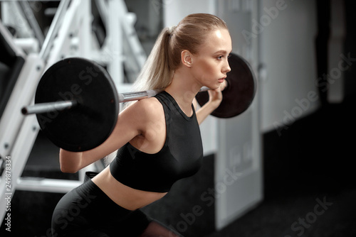 Pretty sportswoman in black top training in gym. © serhiibobyk