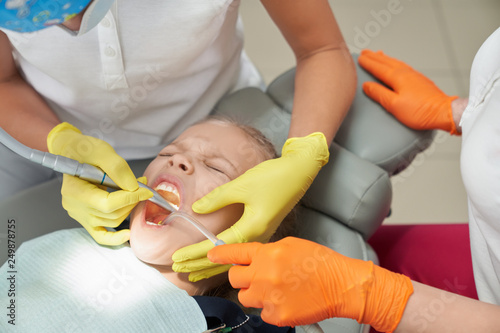 Little girl during painful procedure in dental office