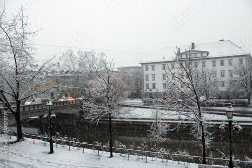Nevicata in città con traffico alberi e fiume photo