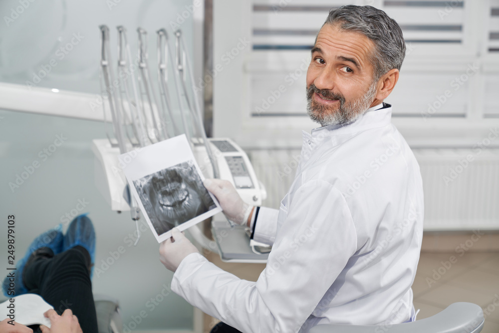Handsome dentist holding dental x-ray. Handsome dentist holding dental x-ray.
