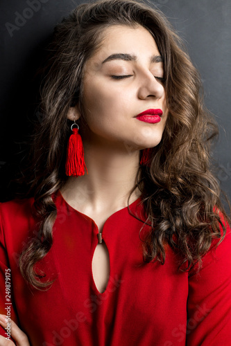 Portrait of a beautiful Indian girl with red lipstick and dress on a black  background. Woman with well-groomed dark hair. Stock Photo