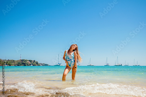 Beautiful young woman with long hair in a blue swimsuit standing in the sea and relax on the beach on Phuket, Thailand
