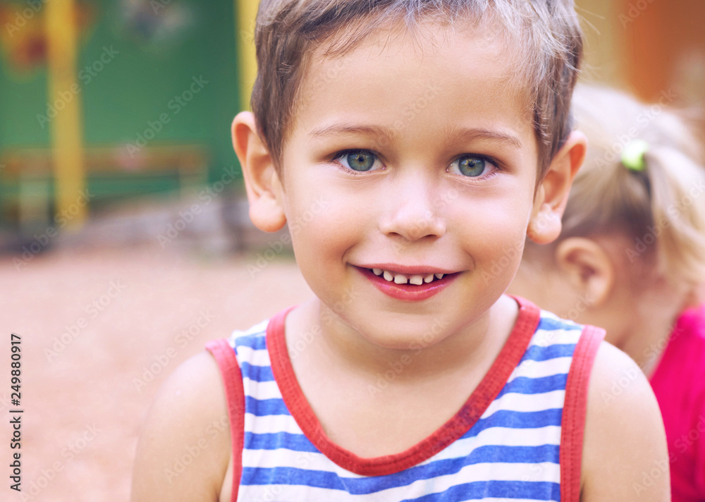 Funny cute happy child playing on the playground. The emotion of happiness, fun, joy. Smile of a cute boy in striped t-shirt. Funny cute happy child playing on the playground. The emotion of happiness, fun, joy. Smile of a cute boy in striped t-shirt.