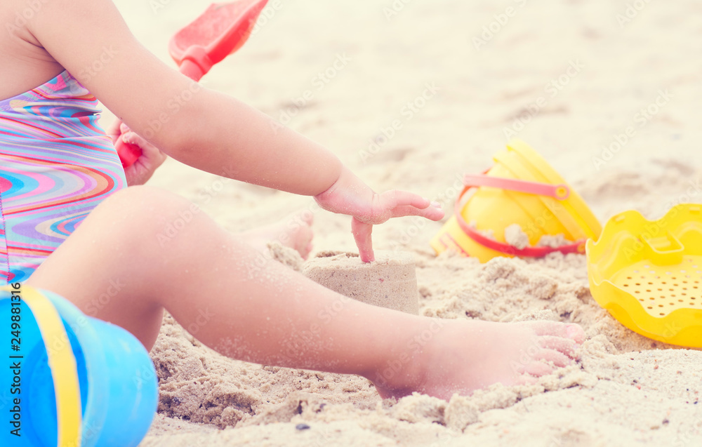 Little blonde baby girl playing with sand on the beach using plastic toys. Little blonde baby girl playing with sand on the beach using plastic toys.