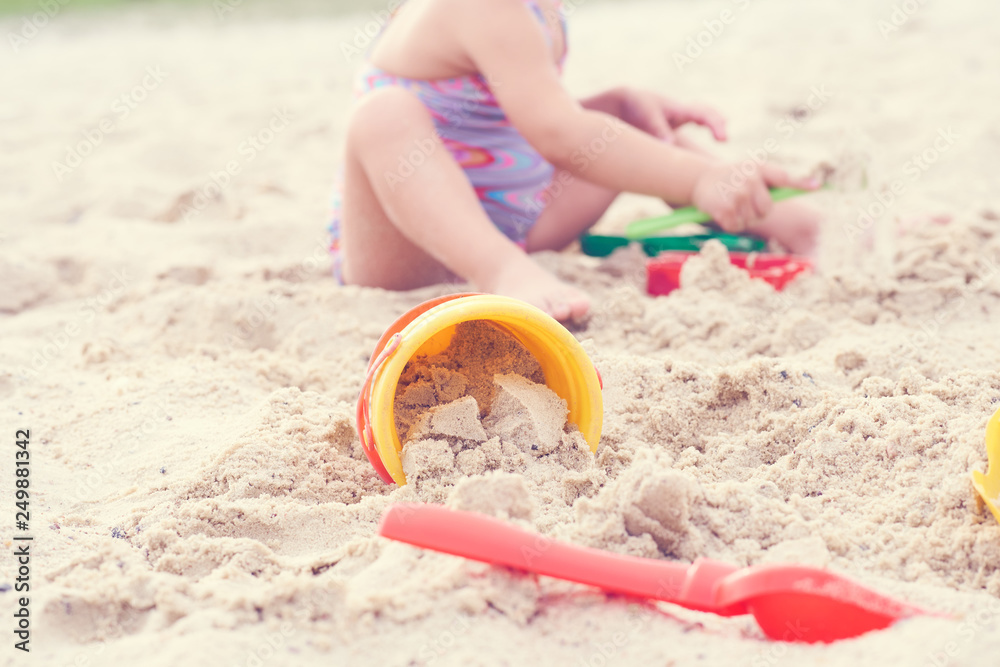 Little blonde baby girl playing with sand on the beach using plastic toys. Little blonde baby girl playing with sand on the beach using plastic toys.