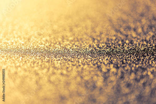 Abstract shiny golden background with bokeh and defocused lights. Glitter glowing texture pattern.