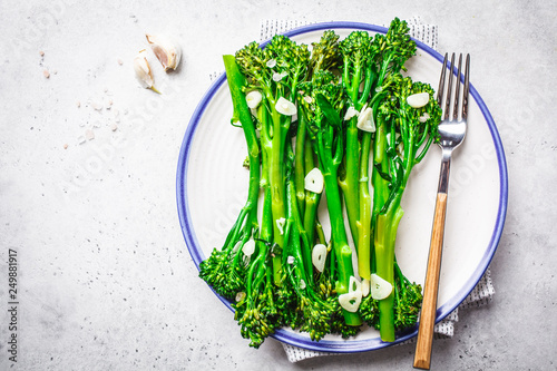 Boiled broccolini with garlic on a white plate. photo