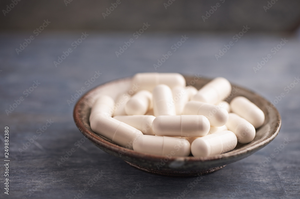 Beta-alanine capsules. Bodybuilding food supplements on rustic wooden background. Close up. Copy space. Beta-alanine capsules. Bodybuilding food supplements on rustic wooden background. Close up. Copy space.