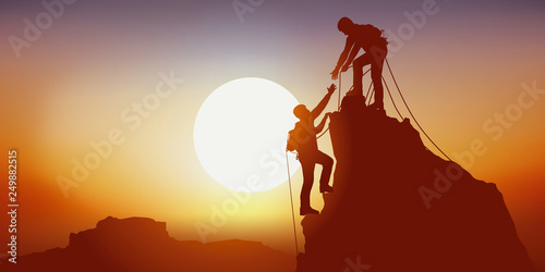 Concept de la solidarité, avec deux alpinistes qui se tendent la main en arrivant au sommet d’une montagne, après l’avoir escalader avec succès photo