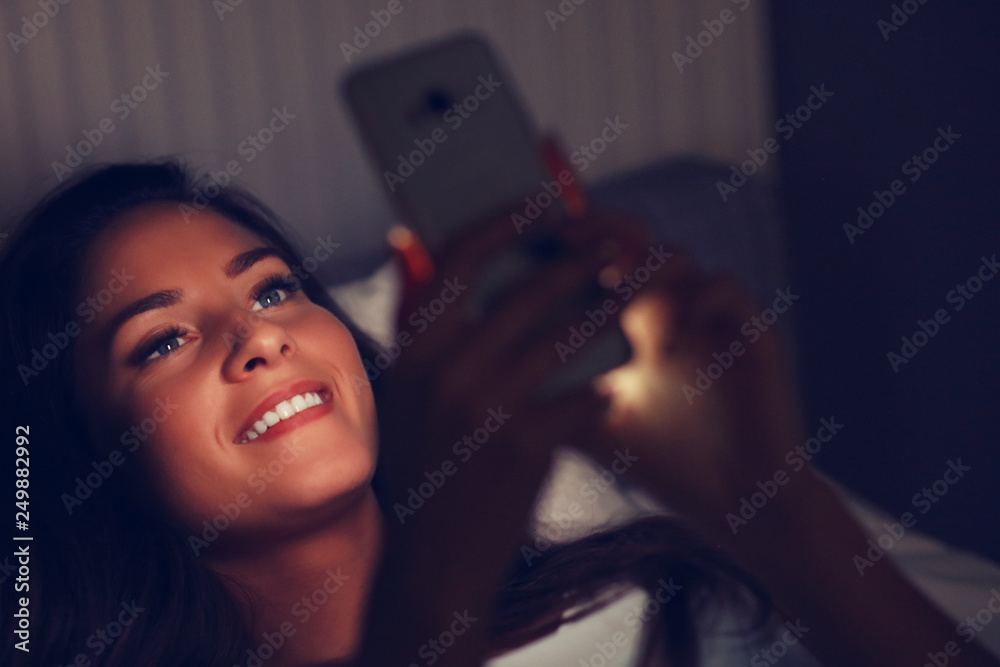 Young beautiful woman resting in bed with smartphone Young beautiful woman resting in bed with smartphone