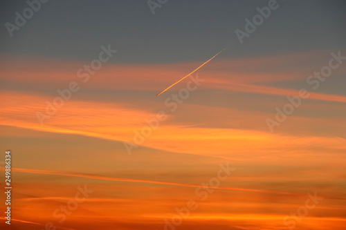 Orange sunset in the clouds in the evening sky in winter © elena