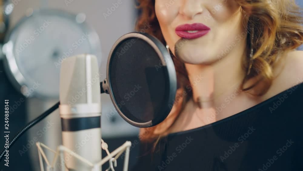 Beautiful face of a singer with bare shoulders singing into a ...