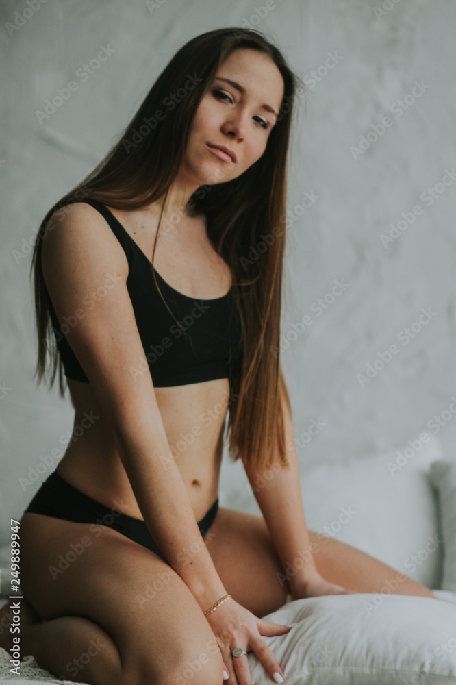 Beautiful tender girl in black lingerie is sitting on the bed. A young woman basks in bed with white linens. The girl woke up and enjoys a good morning. Beautiful tender girl in black lingerie is sitting on the bed. A young woman basks in bed with white linens. The girl woke up and enjoys a good morning.