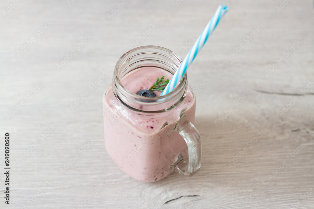 blueberrie smoothie in a jar mug with a straw on table