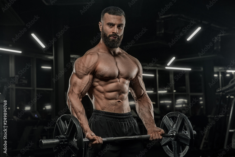 Handsome man with big muscles, posing at the camera in the gym Handsome man with big muscles, posing at the camera in the gym