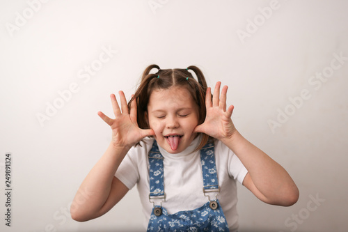 funny girl child builds faces, shows tongue