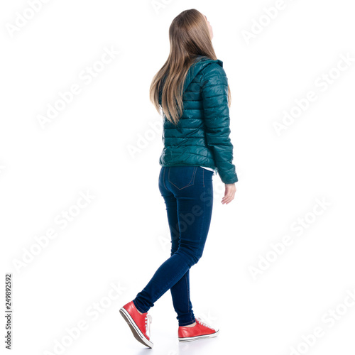 Woman in jeans and jacket walking goes looking on white background. Isolation, back view photo