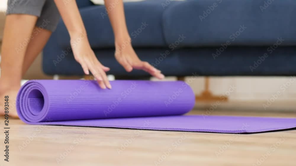 Young asian woman rolling yoga mat to perform yoga asanas safely and comfortably in living room at home. Young asian woman rolling yoga mat to perform yoga asanas safely and comfortably in living room at home.