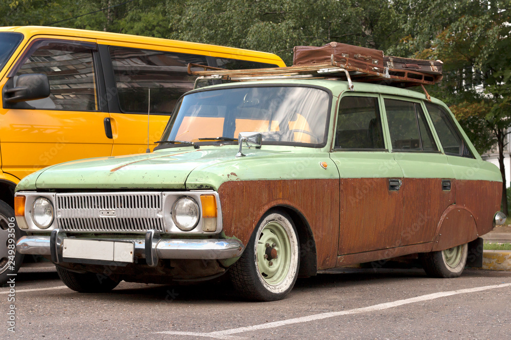 Fototapeta premium Vintage car with suitcases on the roof. Abandoned auto in the parking lot