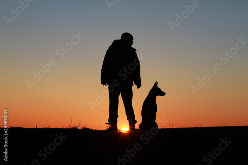 A man and a dog against the backdrop of an incredible sunset