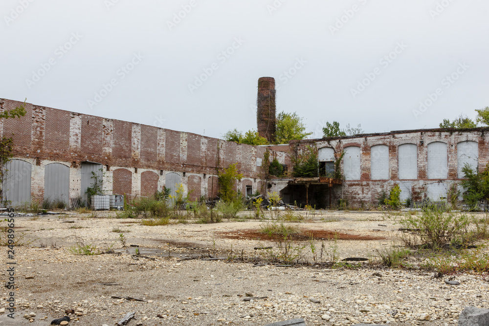 Behind the remains of an abandoned factory with tall brick chimney