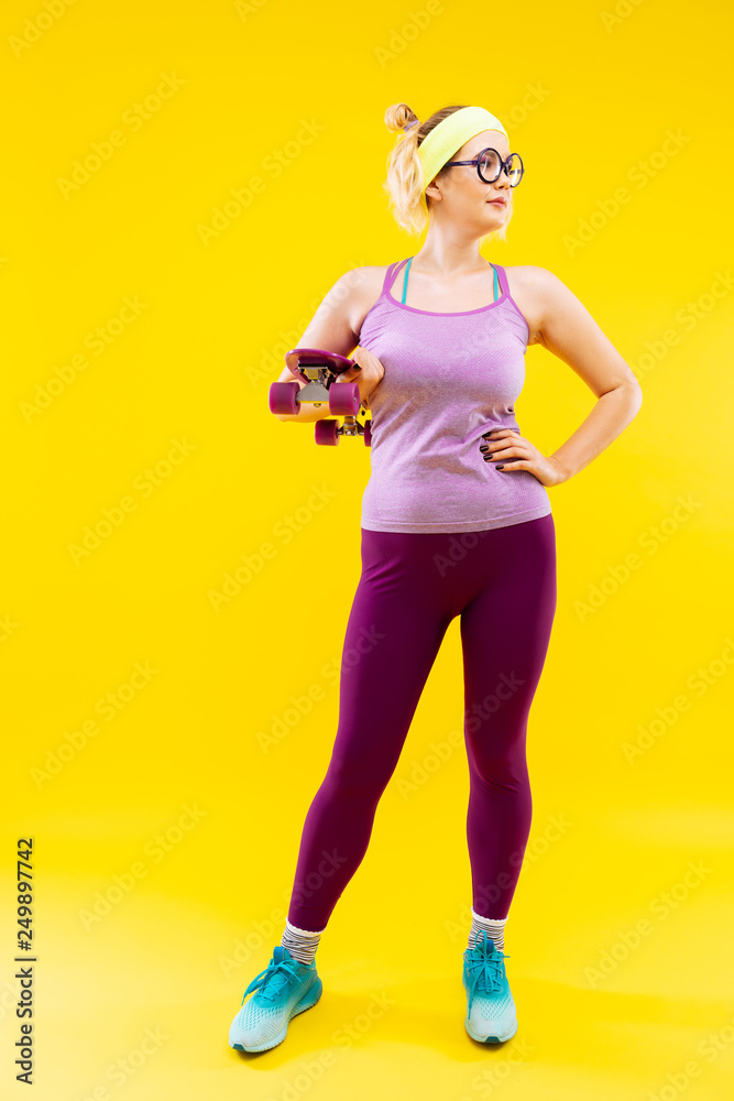 Young woman wearing bright sneakers holding skateboard Young woman wearing bright sneakers holding skateboard