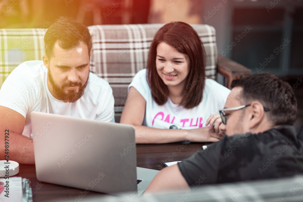 Obraz premium Businessmen discuss the deal and control it online, in a cafe on the street. A girl and two guys.