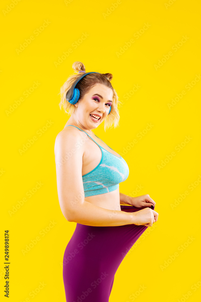 Young woman with earphones feeling proud after losing kilos Young woman with earphones feeling proud after losing kilos