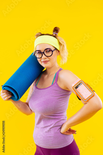 Woman wearing purple sport clothes holding blue sport mat