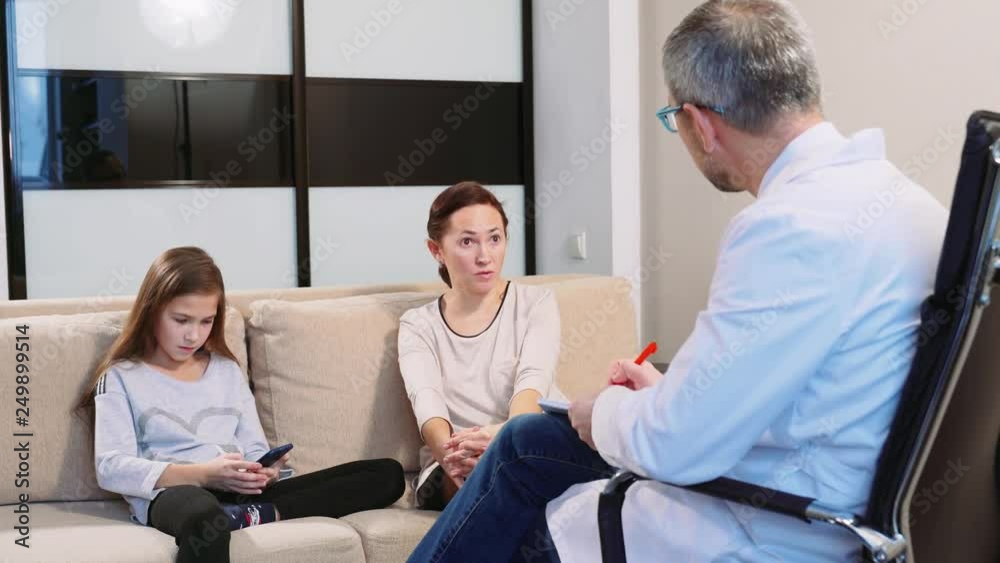 Middle-aged woman with her daughter at the reception in the office of a child psychologist. Daughter does not obey her mother. Middle-aged woman with her daughter at the reception in the office of a child psychologist. Daughter does not obey her mother.