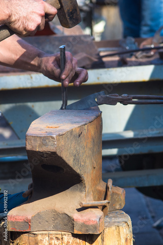 blacksmith performs the forging of hot glowing metal on the anvil