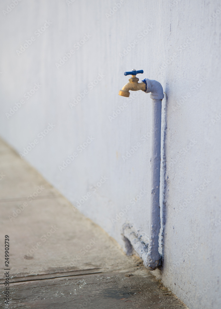 Faucet against old building with lavender pipe Faucet against old building with lavender pipe