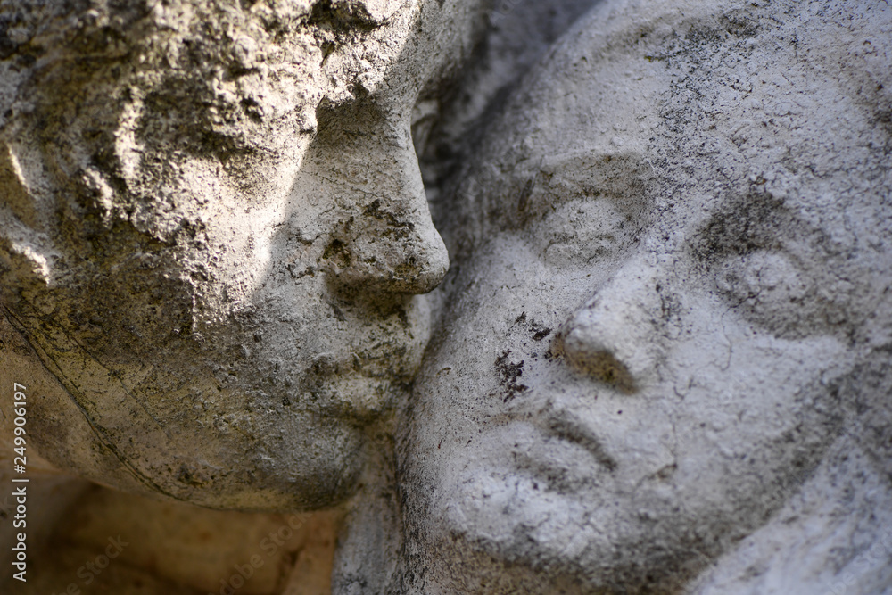 Naklejka premium Partial view of an old, weathered sandstone sculpture. Two faces that are very close to each other.