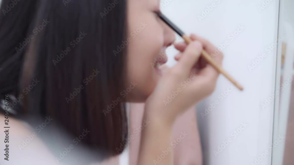 Beautiful Asian woman using eyeshadow make up in front mirror, Happy female using beauty cosmetics to improve herself ready to working in bedroom at home. Lifestyle women relax at home concept. Beautiful Asian woman using eyeshadow make up in front mirror, Happy female using beauty cosmetics to improve herself ready to working in bedroom at home. Lifestyle women relax at home concept.