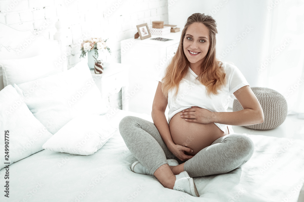 Smiling future mother lifting her t-shirt and presenting round stomach Smiling future mother lifting her t-shirt and presenting round stomach