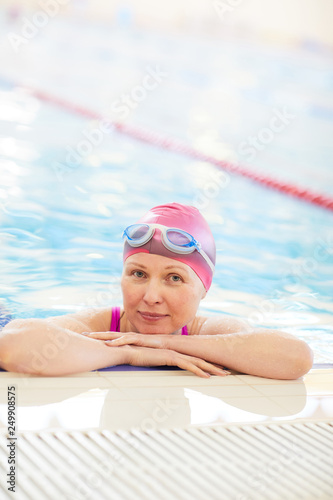 Portrait of active senior woman in swimming pool  leaning on border and looking at camera  copy space