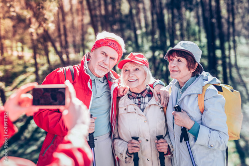 Three beaming retired people feeling cheerful while hiking