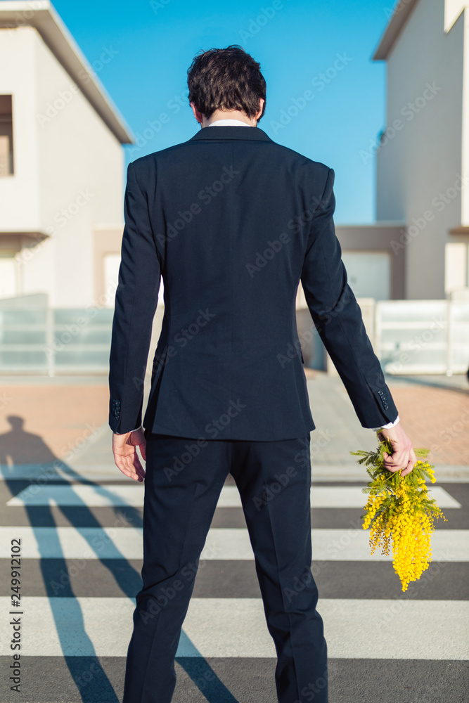 Ragazzo vestito elegante sta per fare un regalo di fiori mimose per la  festa della donna di fronte casa. Gesto di cavalleria. foto de Stock |  Adobe Stock
