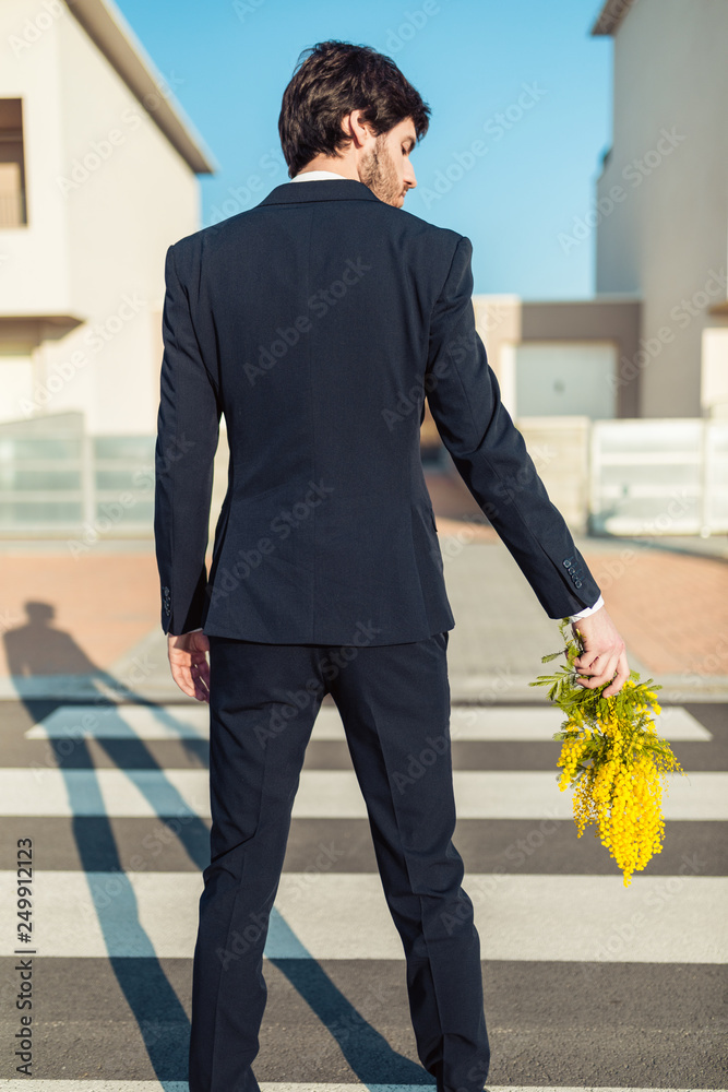 Ragazzo vestito elegante sta per fare un regalo di fiori mimose per la  festa della donna di fronte casa. Stock Photo | Adobe Stock