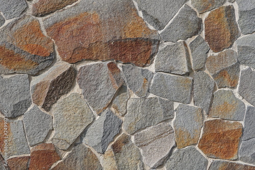 Decorative wall of artificial torn stone in brown tones. Stone masonry in geometric pattern as background or texture. Decorative wall of artificial torn stone in brown tones. Stone masonry in geometric pattern as background or texture.