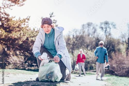 Woman coming with plastic bag helping woman cleaning the park