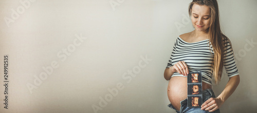 Pregnant woman holding ultrasound image.