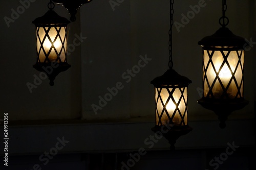 A group of black steel lanterns hanging from a dark room ceiling with dark night background 